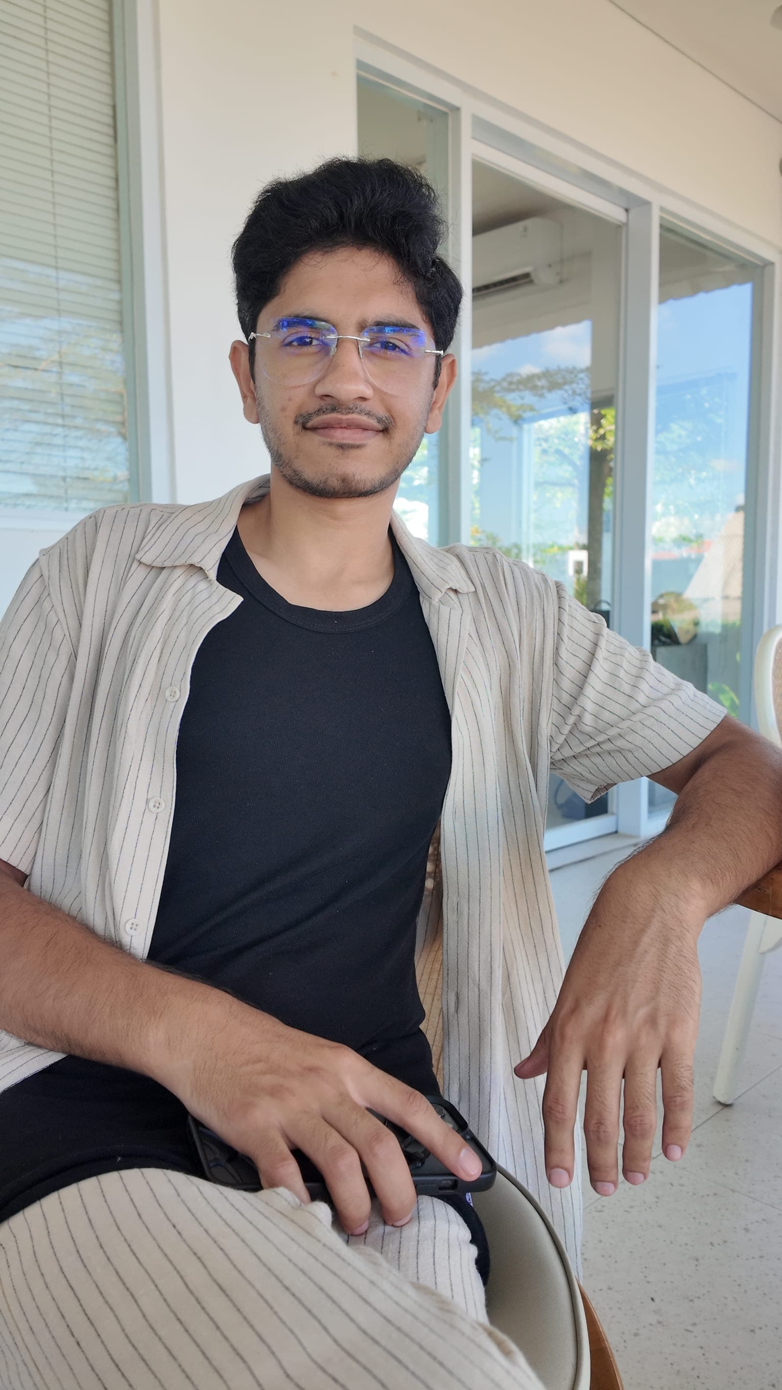 Waseem on the veranda, direct gaze, thinking through a build